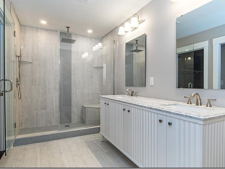 Remodeled bathroom by Avexa with glass walk-in shower, bench, and double vanity
