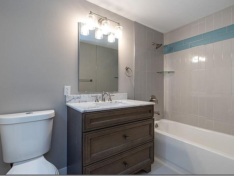 Remodeled bathroom by Avexa with furniture-style wood vanity and marble top